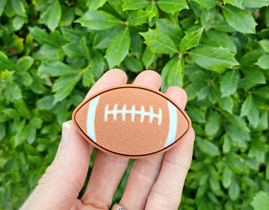 hand holding a 3d football clicker. Green background