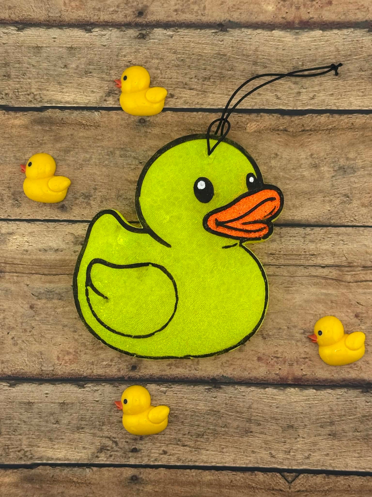 Green rubber duck toy with small yellow rubber ducks on a wooden surface
