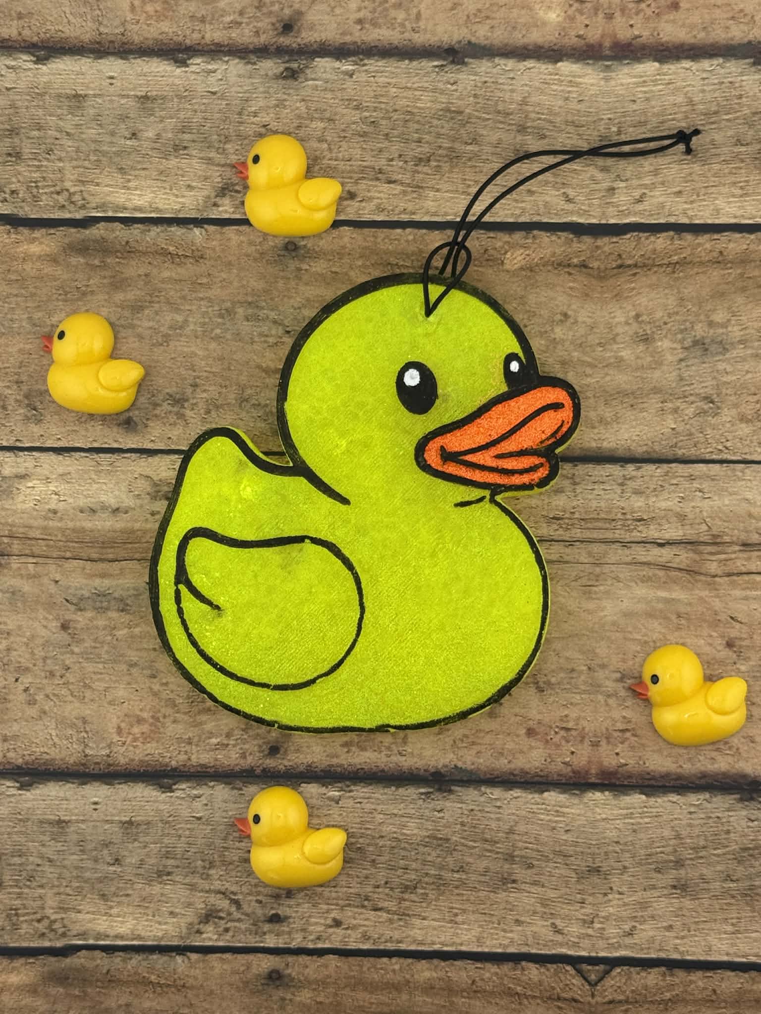 Green rubber duck toy with small yellow rubber ducks on a wooden surface