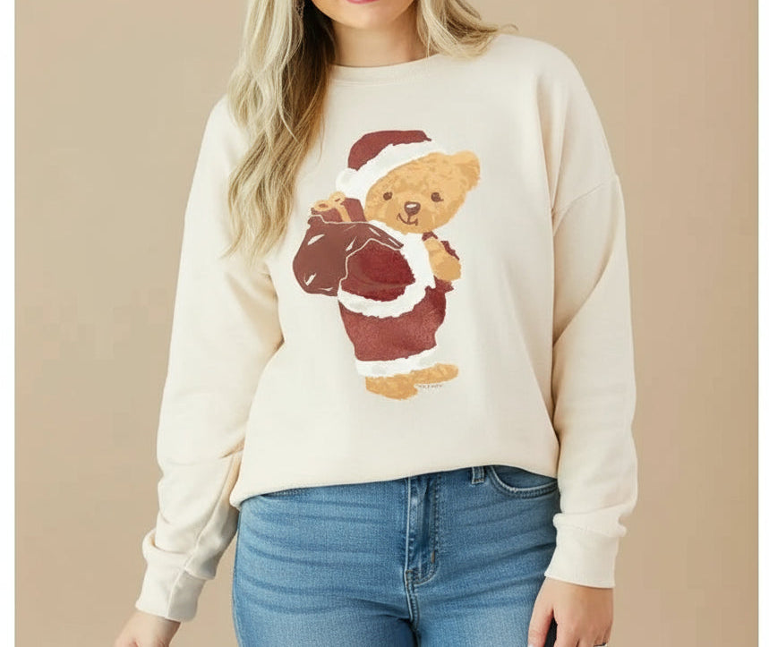 Woman wearing a cream sweatshirt with a santa bear design on front and blue jeans. Neutral studio background