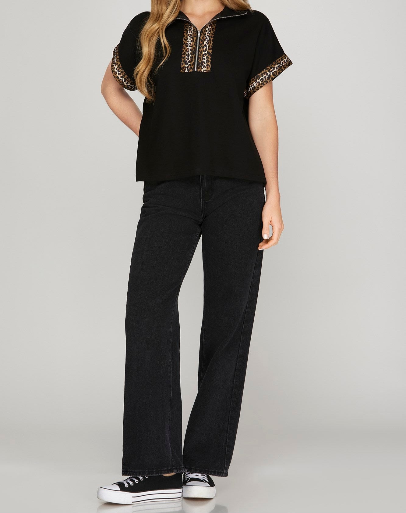 Woman wearing a black top with decorative sleeves and black pants on a gray background