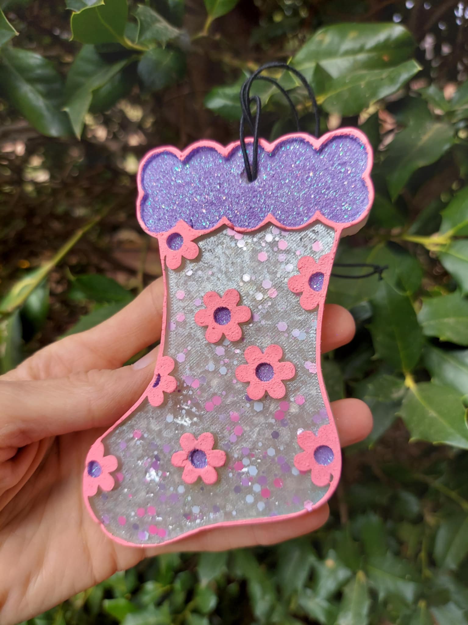 silver freshie with pink flowers and purple trim held in front of greenery