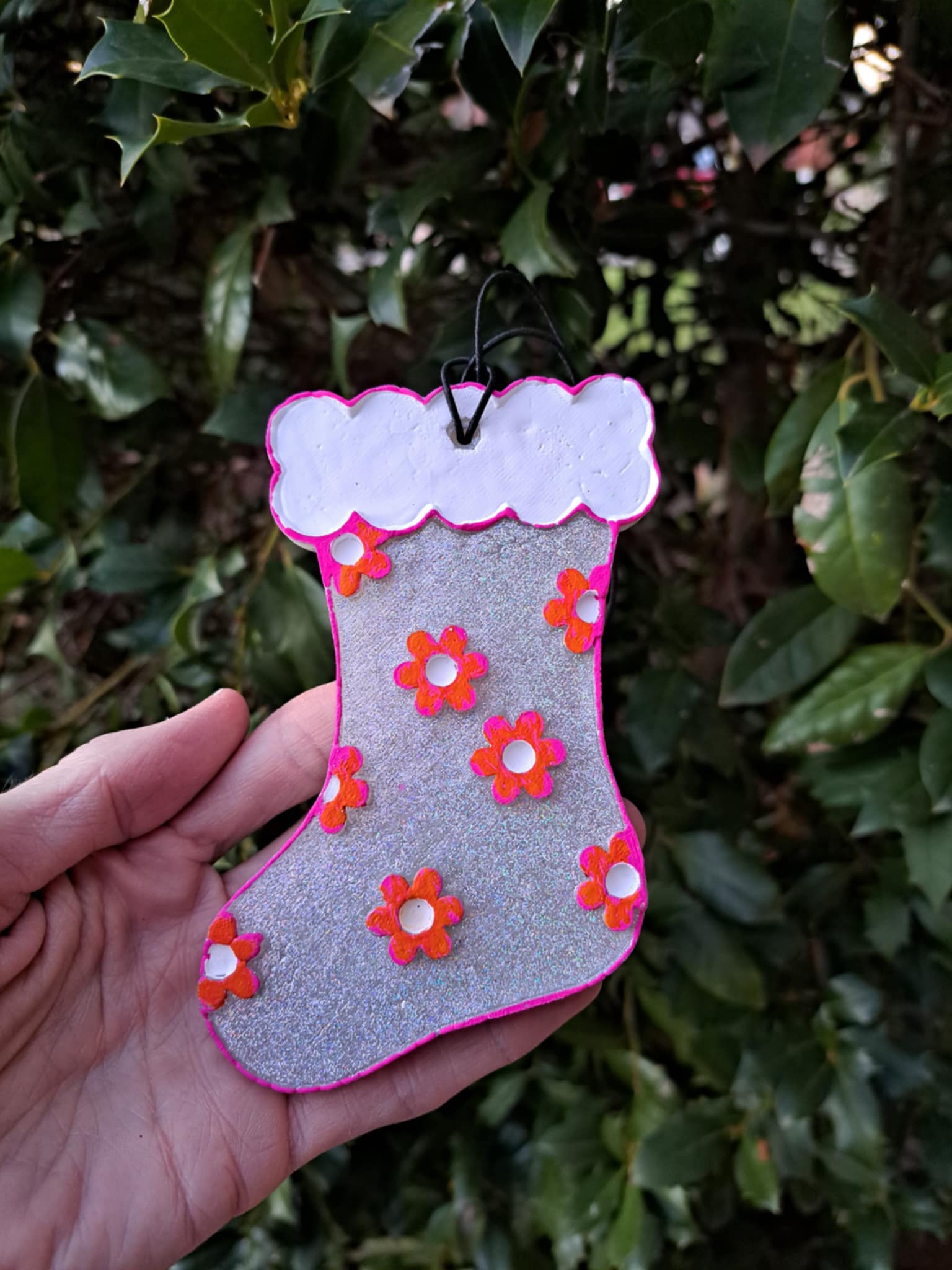 metallic stocking freshie held in hand against a background of greenery