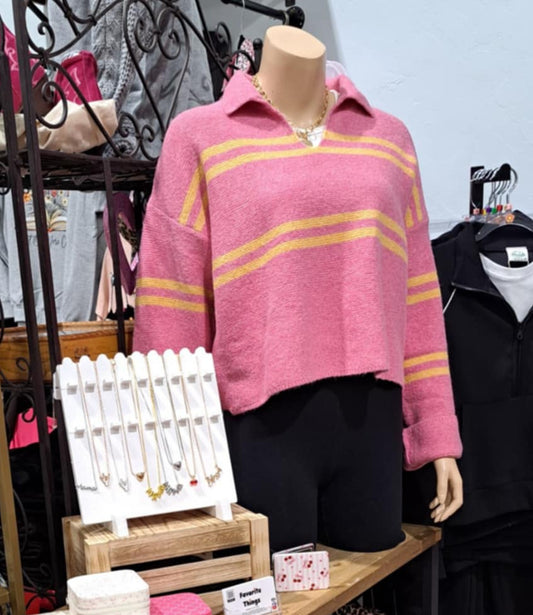 Display of clothing and accessories in a store with a mannequin wearing a pink sweater.