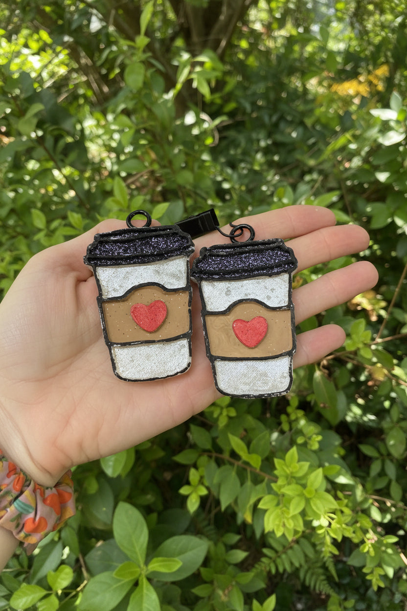 hand holding mug vent clips against a greenery background