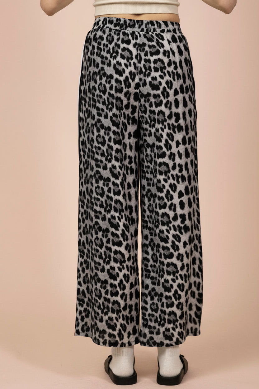 Leopard print pants worn by a person on a beige background