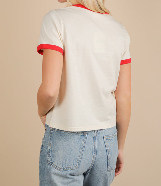 Back view of a person wearing a white shirt with red trim and blue jeans on a beige background
