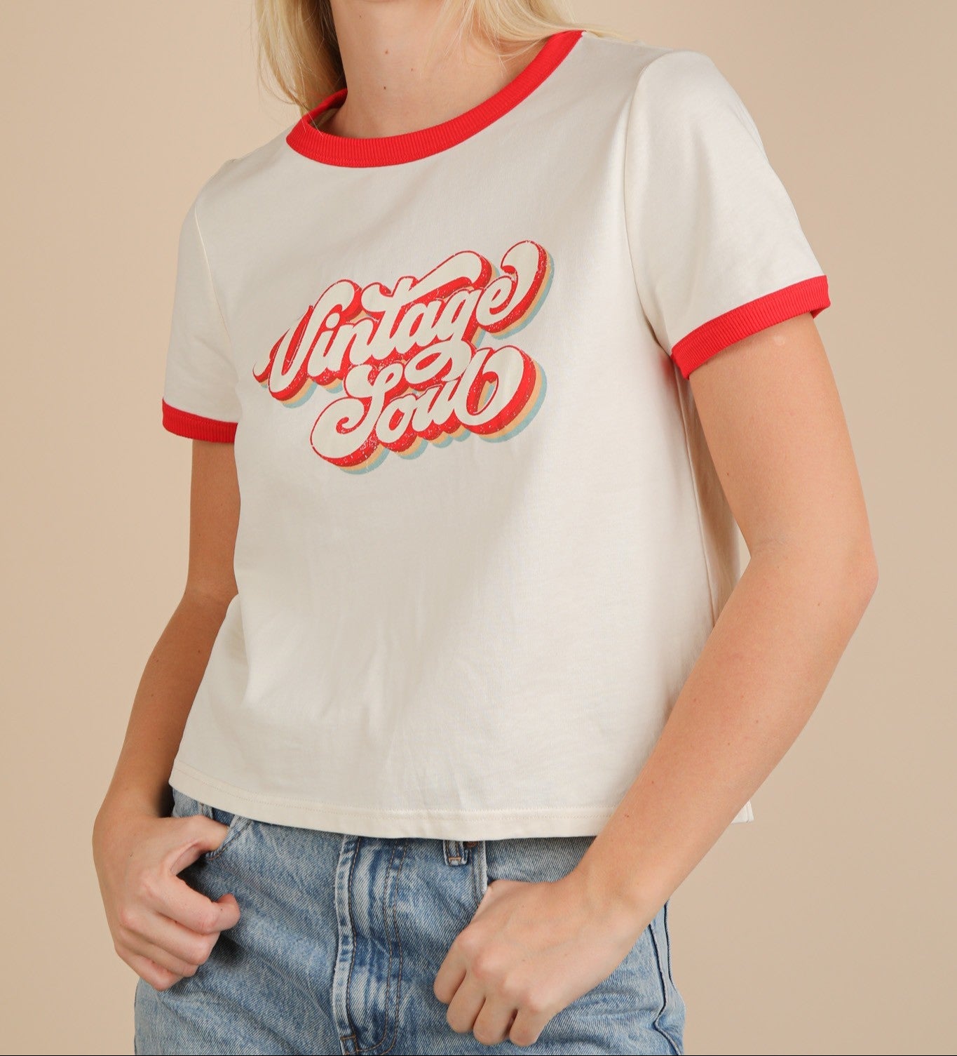 Woman wearing a white t-shirt with red trim and 'Vintage Soul' text on a beige background