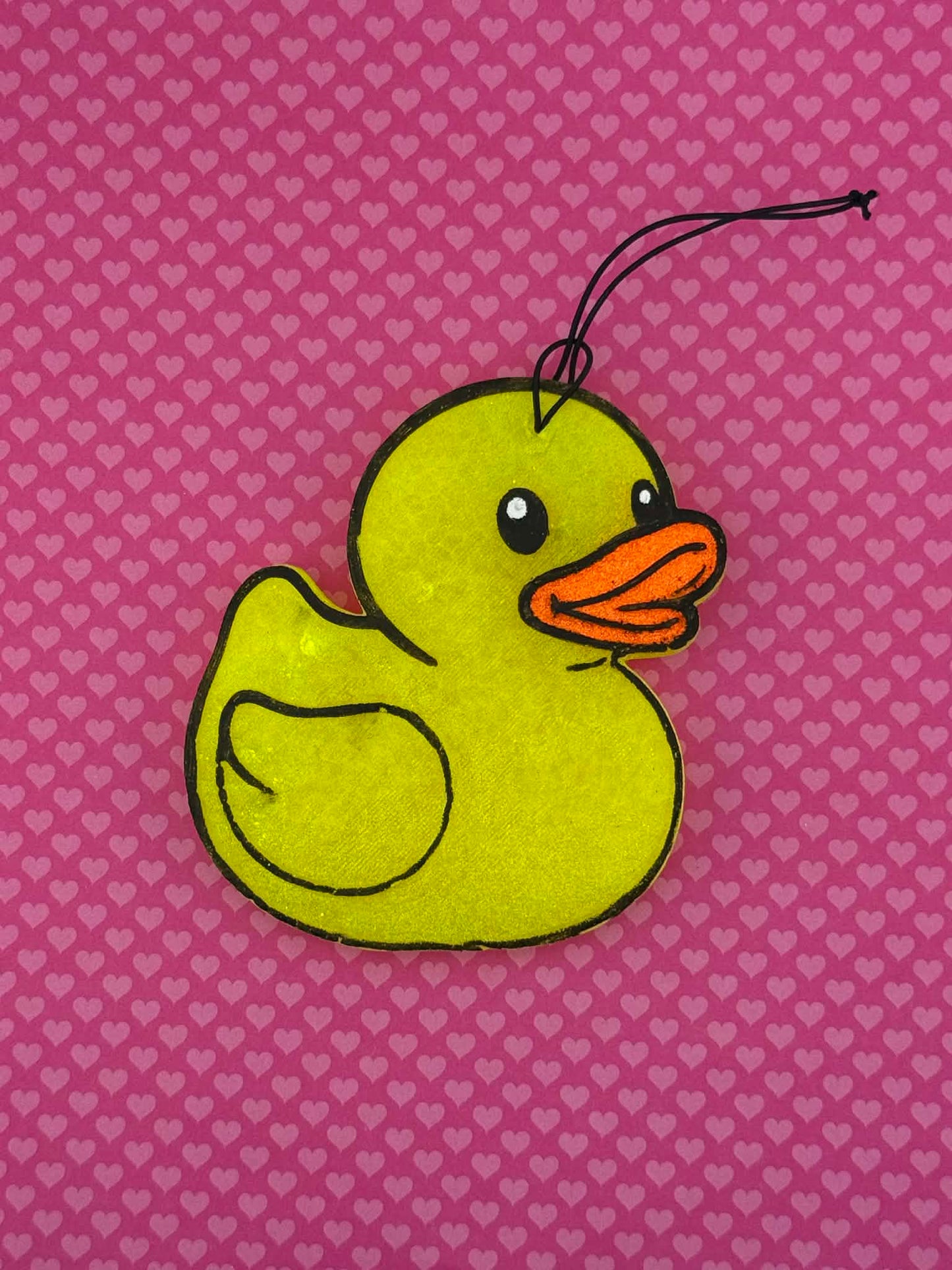 Yellow rubber duck freshie on a pink background with heart patterns