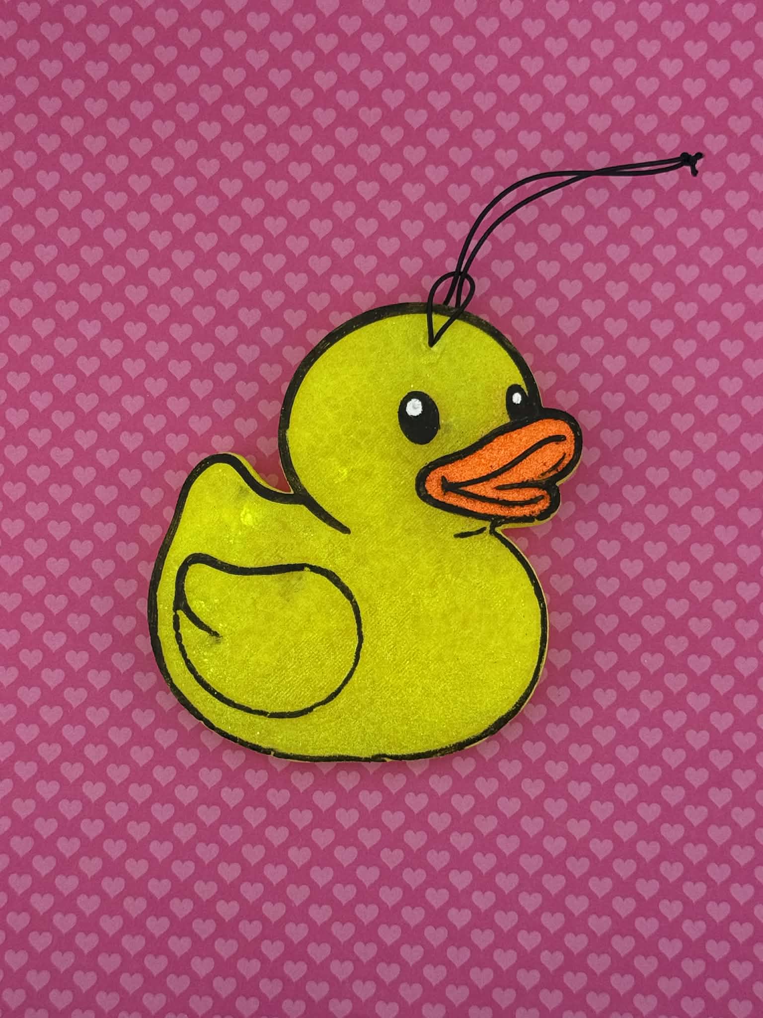 Yellow rubber duck freshie on a pink background with heart patterns