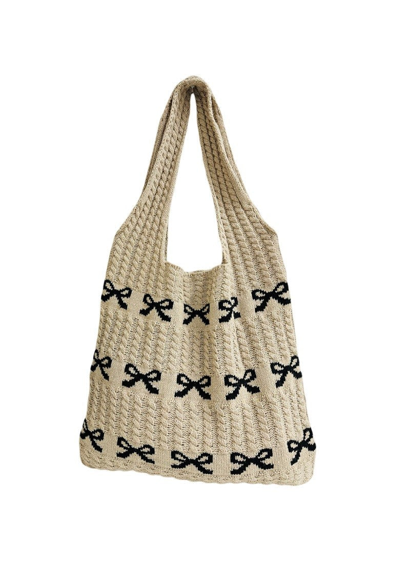 Beige woven handbag with black bow patterns on a white background