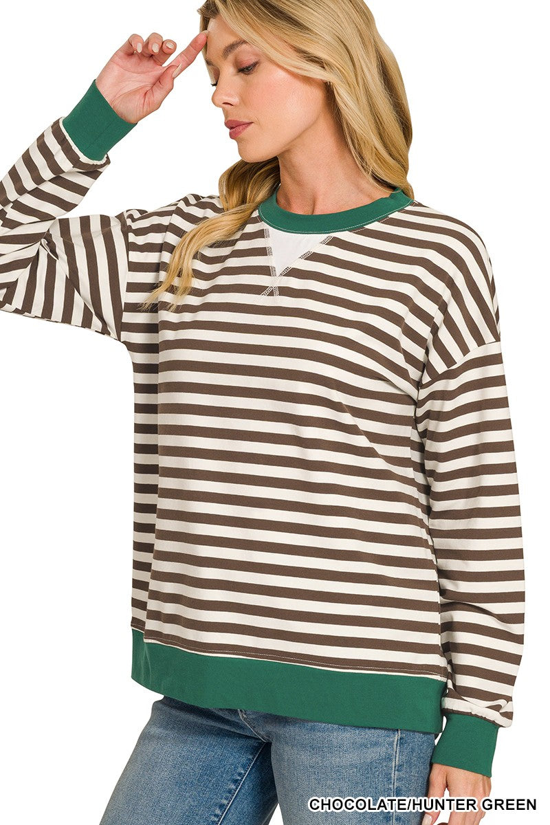 A woman wearing a brown and cream horizontal striped long-sleeve quarter-zip sweatshirt with green ribbed trim, paired with blue jeans, against a white background.