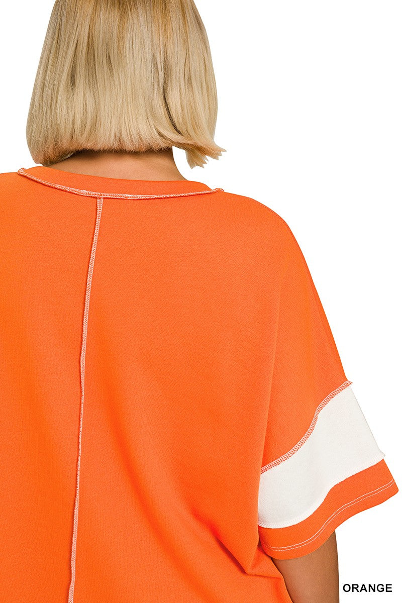 A close-up back view of a person wearing an orange short-sleeve top with a white sleeve stripe and a vertical seam down the back, on a white background.