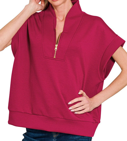 Woman wearing a cabernet-colored short-sleeve top with a zipper on a white background