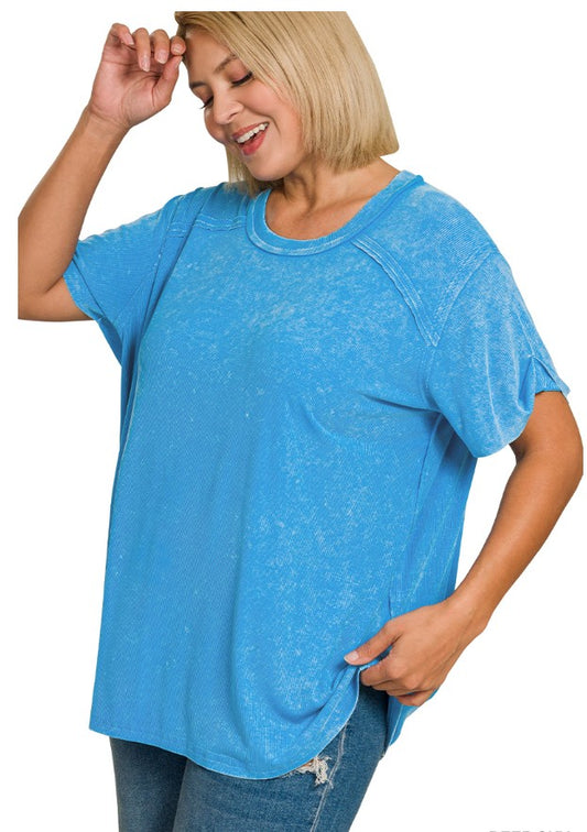 Woman wearing a washed blue ribbed top with reverse stitching in front of a white background 