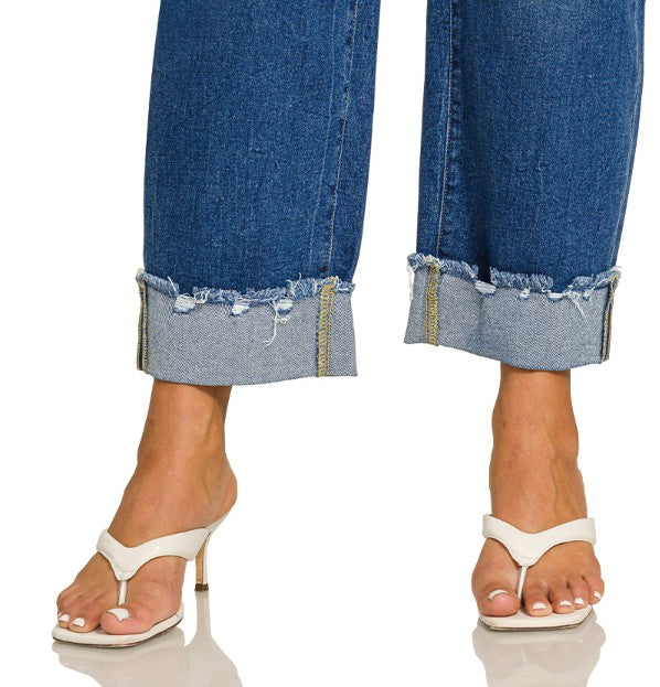 Cropped jeans with frayed hems worn by a person on a white background