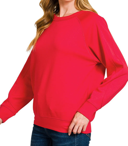 Woman wearing a red sweatshirt with a plain background
